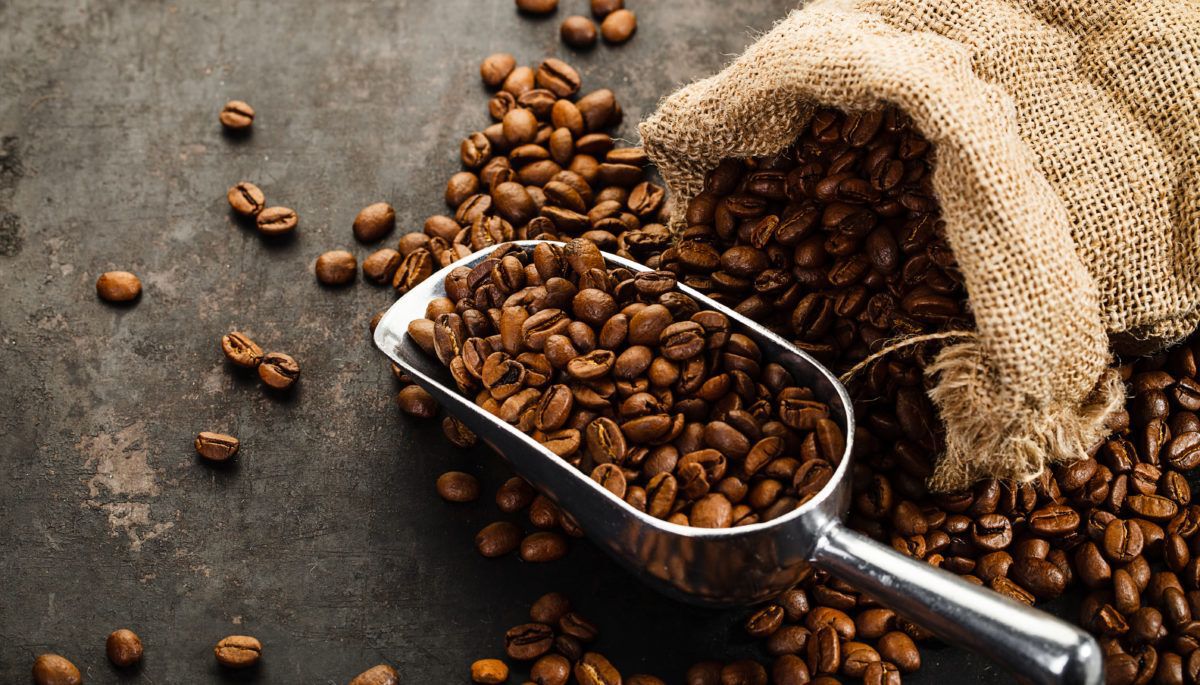 Coffee beans, bag and scoop on old rusty background