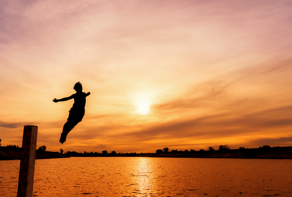 person jumping into a lake