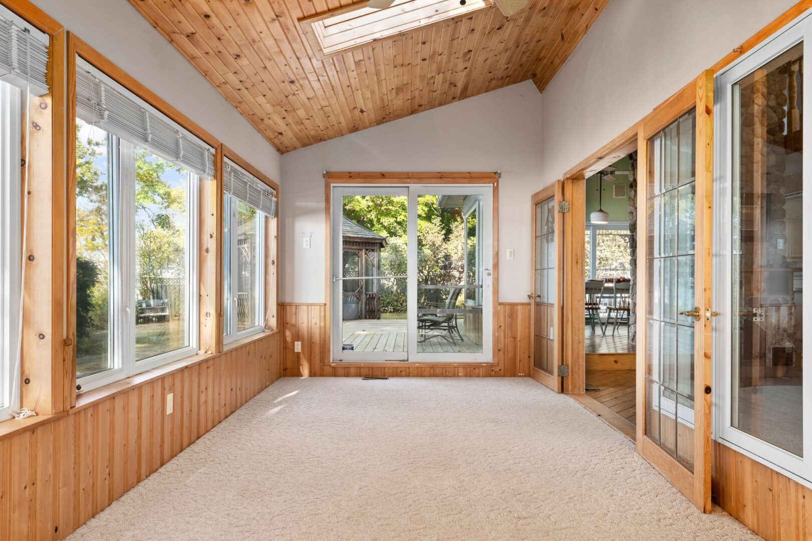 A big sunroom with lots of windows and wood-panelled walls and ceiling.