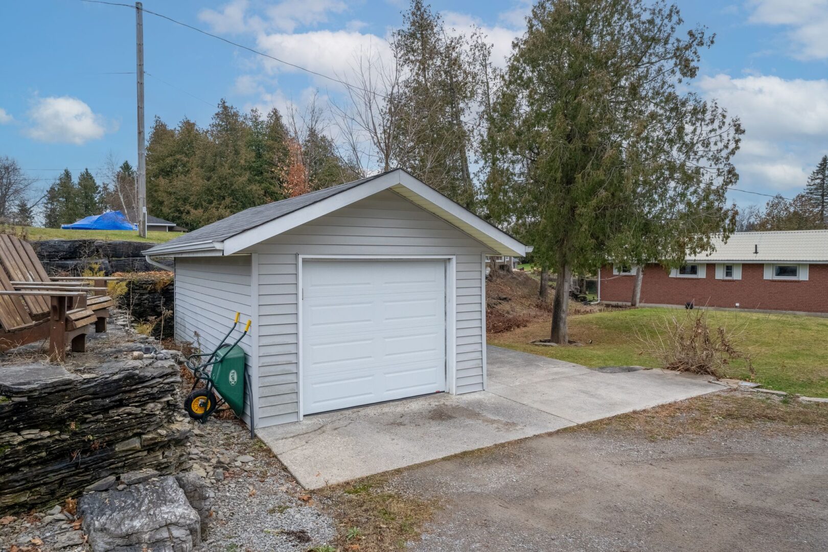 A one-car detached garage with a gravel driveway in front of it.