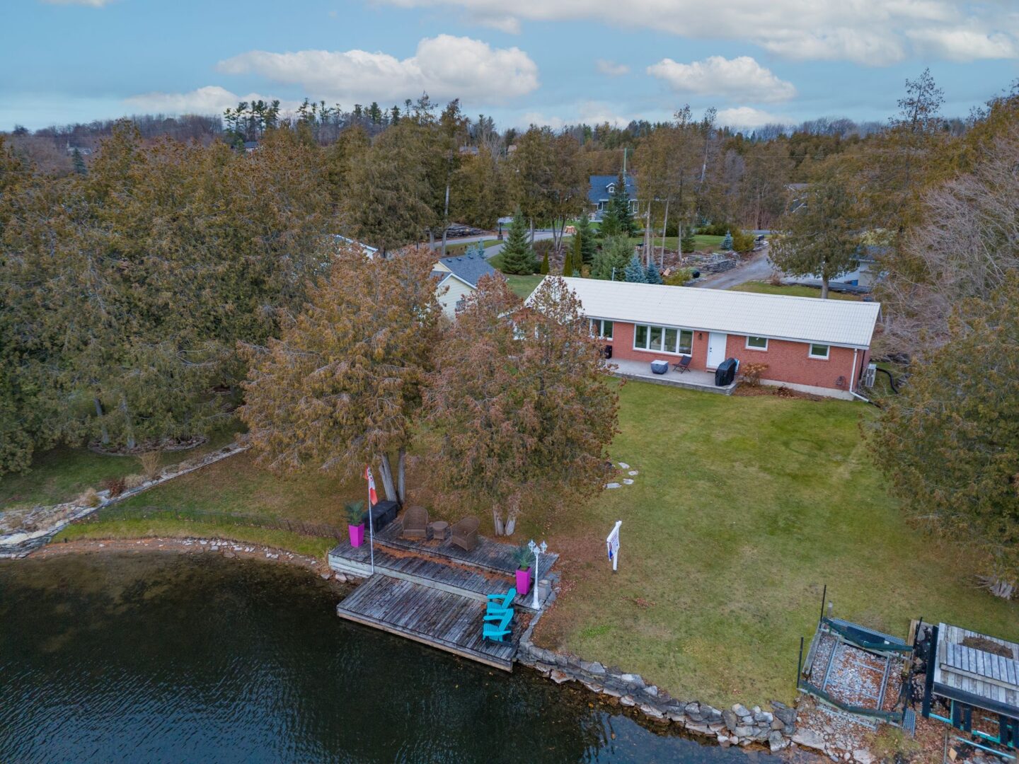 A bungalow on a long lot sits on the shoreline of a river.