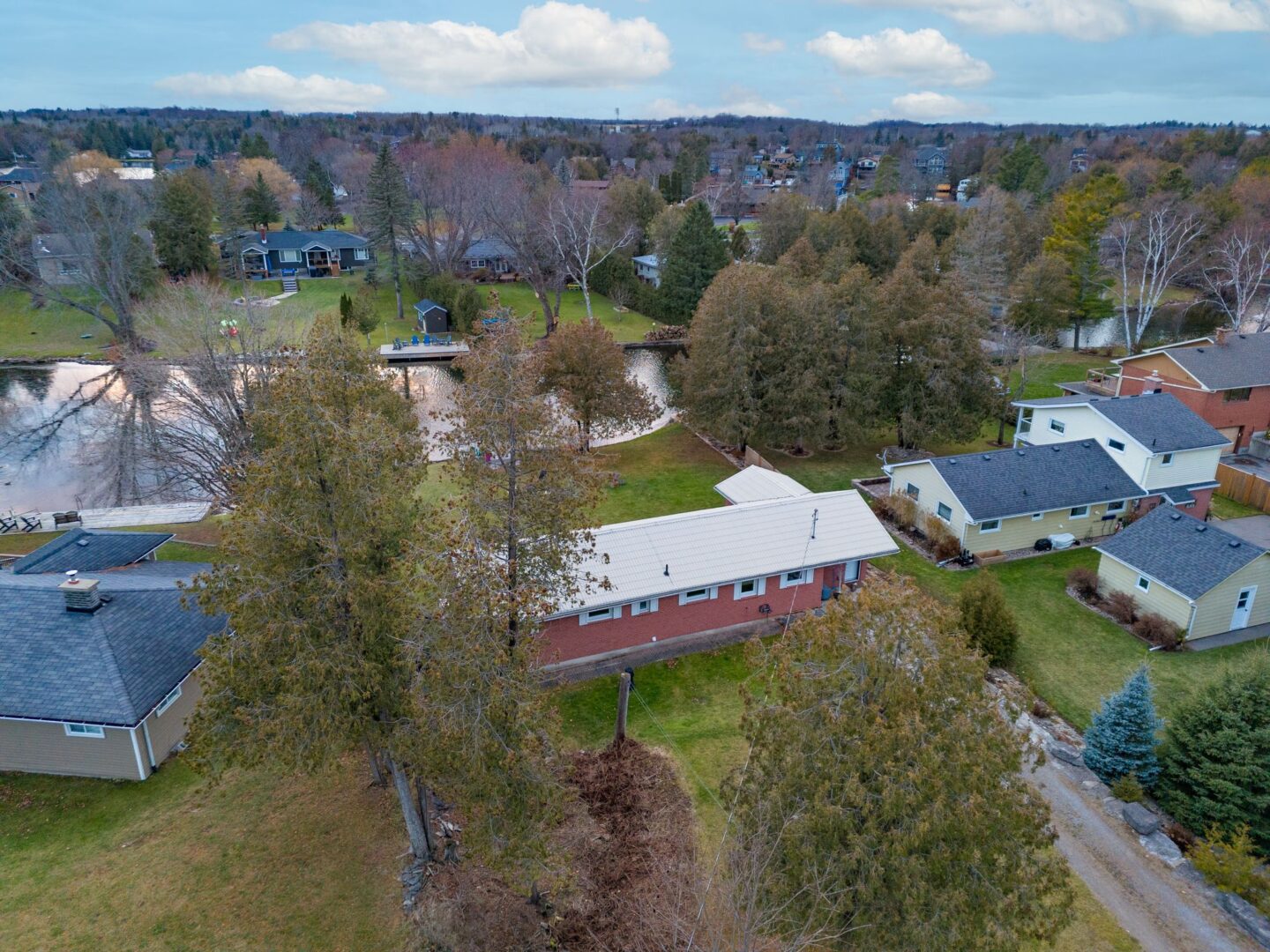 A bungalow on a long lot sits on the shoreline of a river.