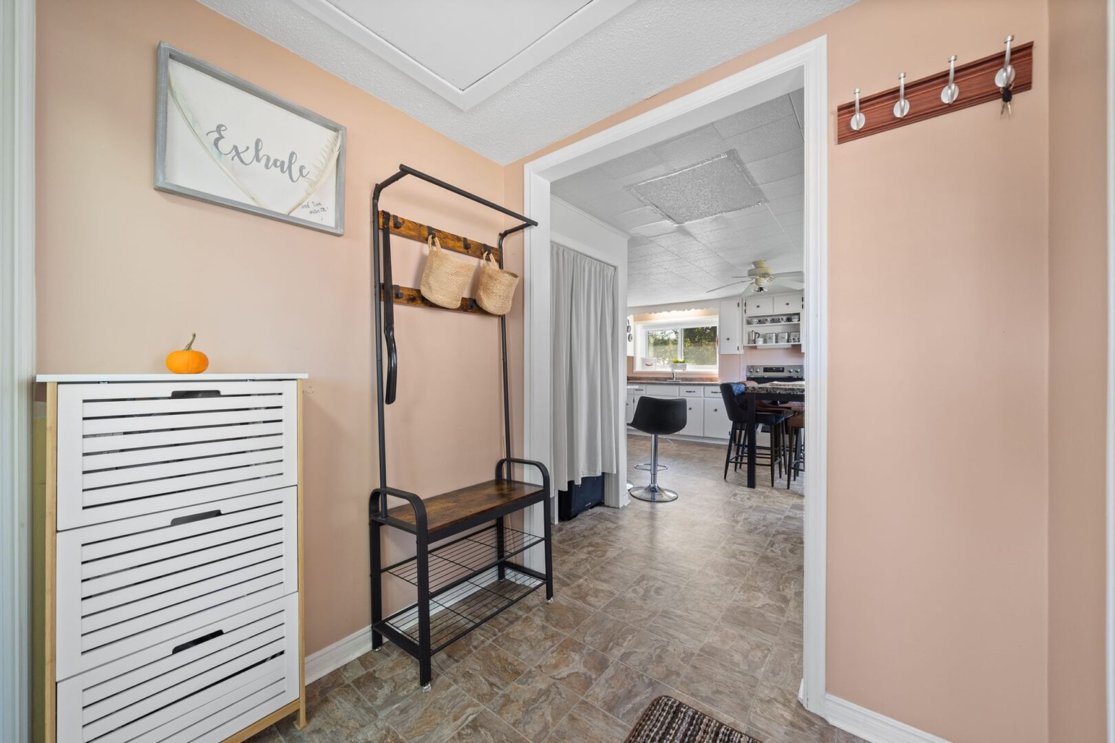 A front entrance area with tile floors, a bench with coat hooks, and peach-coloured walls.
