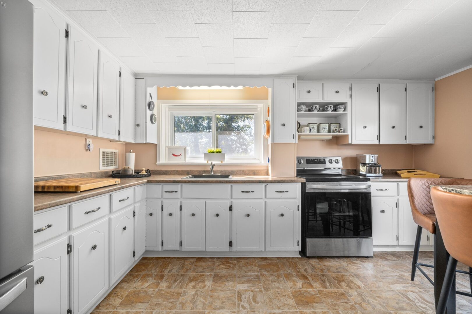 A bright kitchen and dining space with white cupboards and stainless steel appliances.
