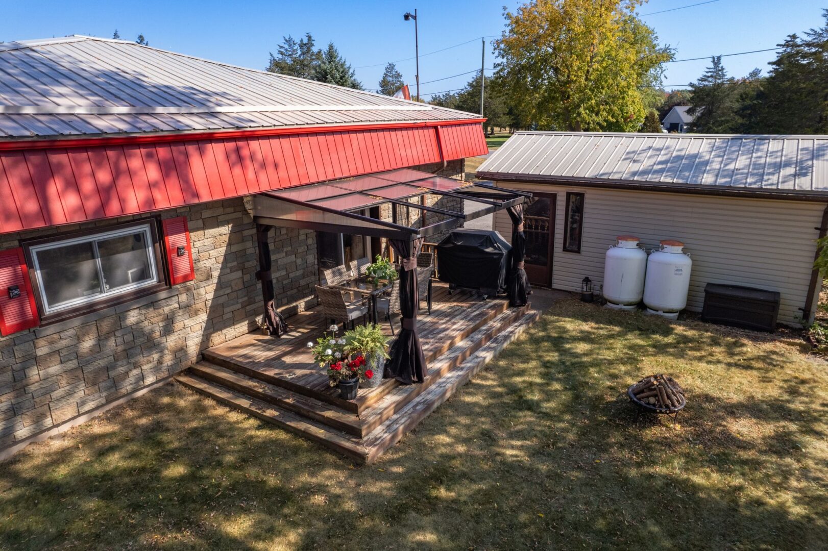 Overhead view of a bungalow property with a shady, grassy yard. A covered deck extends off one side of the home.