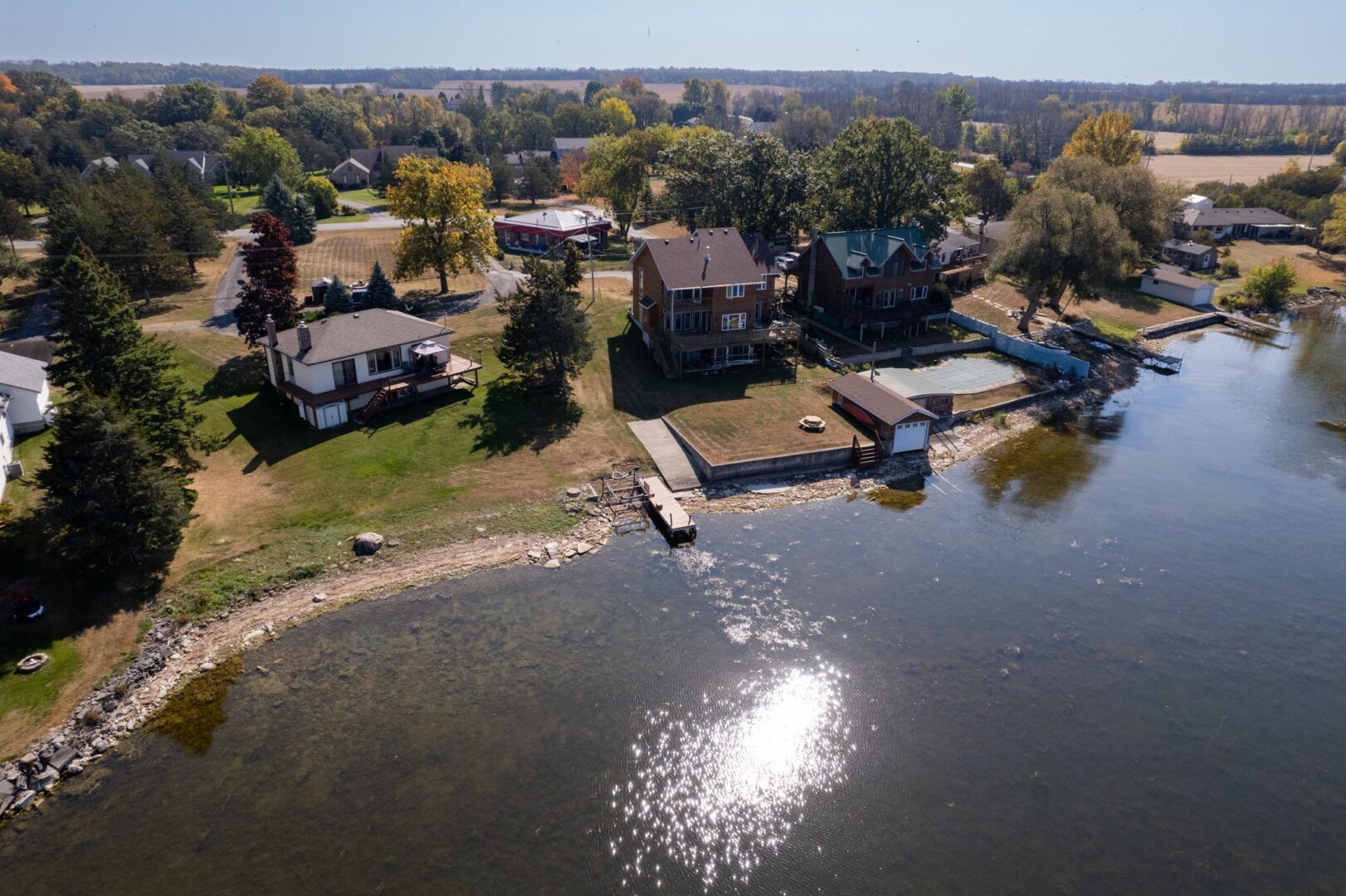 A small dock extends into the water on the shoreline of a residential area.