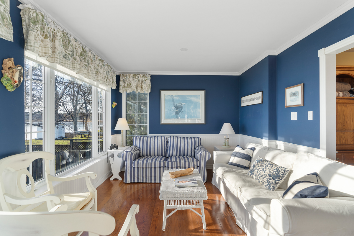 A sunny sitting area with big windows, navy blue accents, and white furniture.
