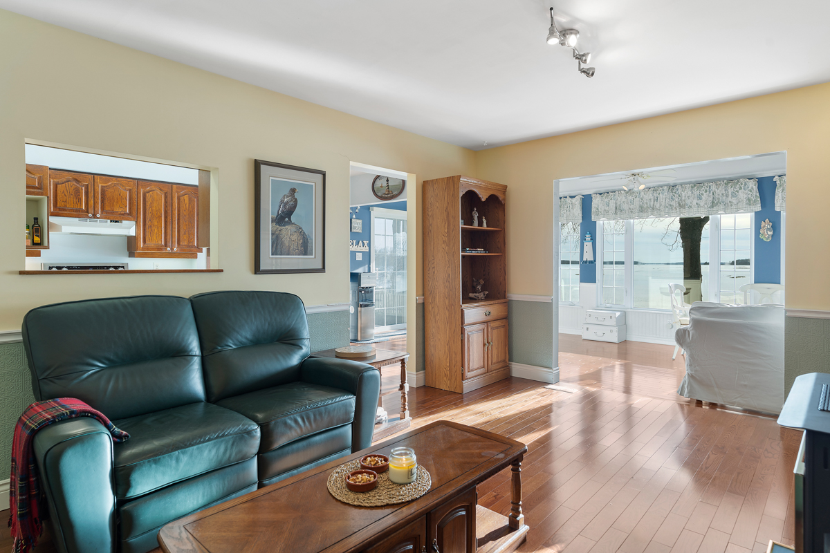 A cozy living area with cushy, dark green couches and hardwood floors.