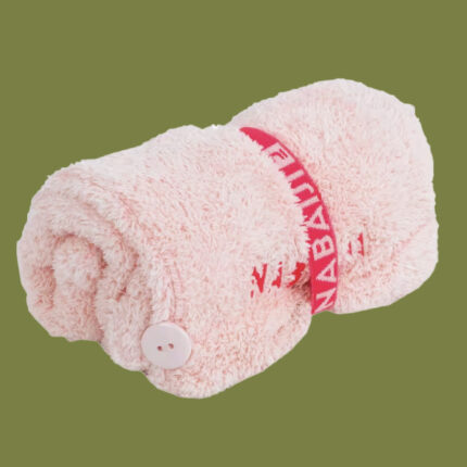 a pink hair towel, wrapped, against a green background