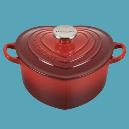a red, heart-shaped dutch oven against a blue background