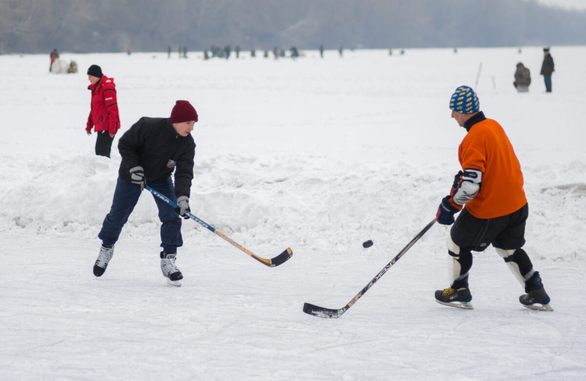 two people play hockey on outdoor ice