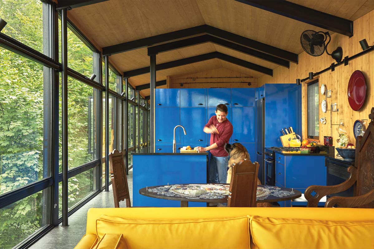 Paul, pictured in red, feeds his dog Jethro a treat in his blue kitchen.