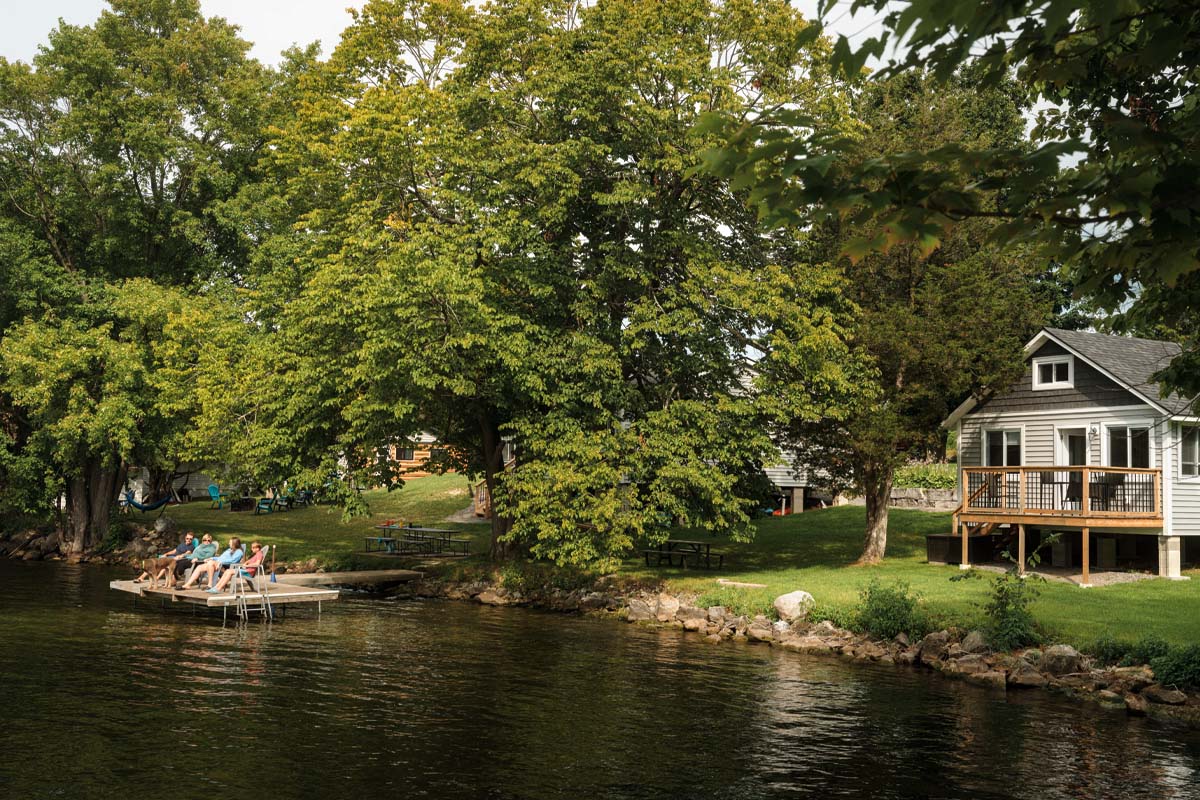 The Bickmores sit on chairs on their dock to the left of the main cottage.