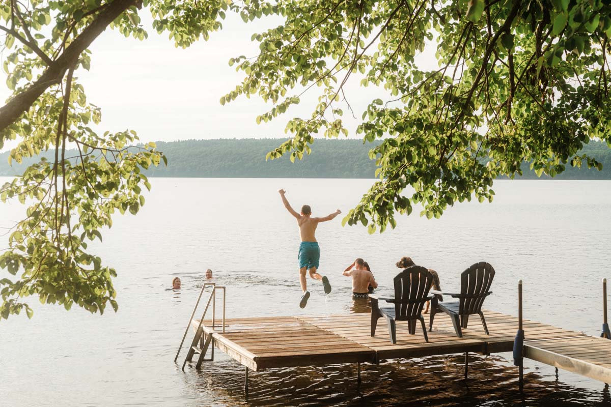 Kaden jumps off the dock into the water where his family is.