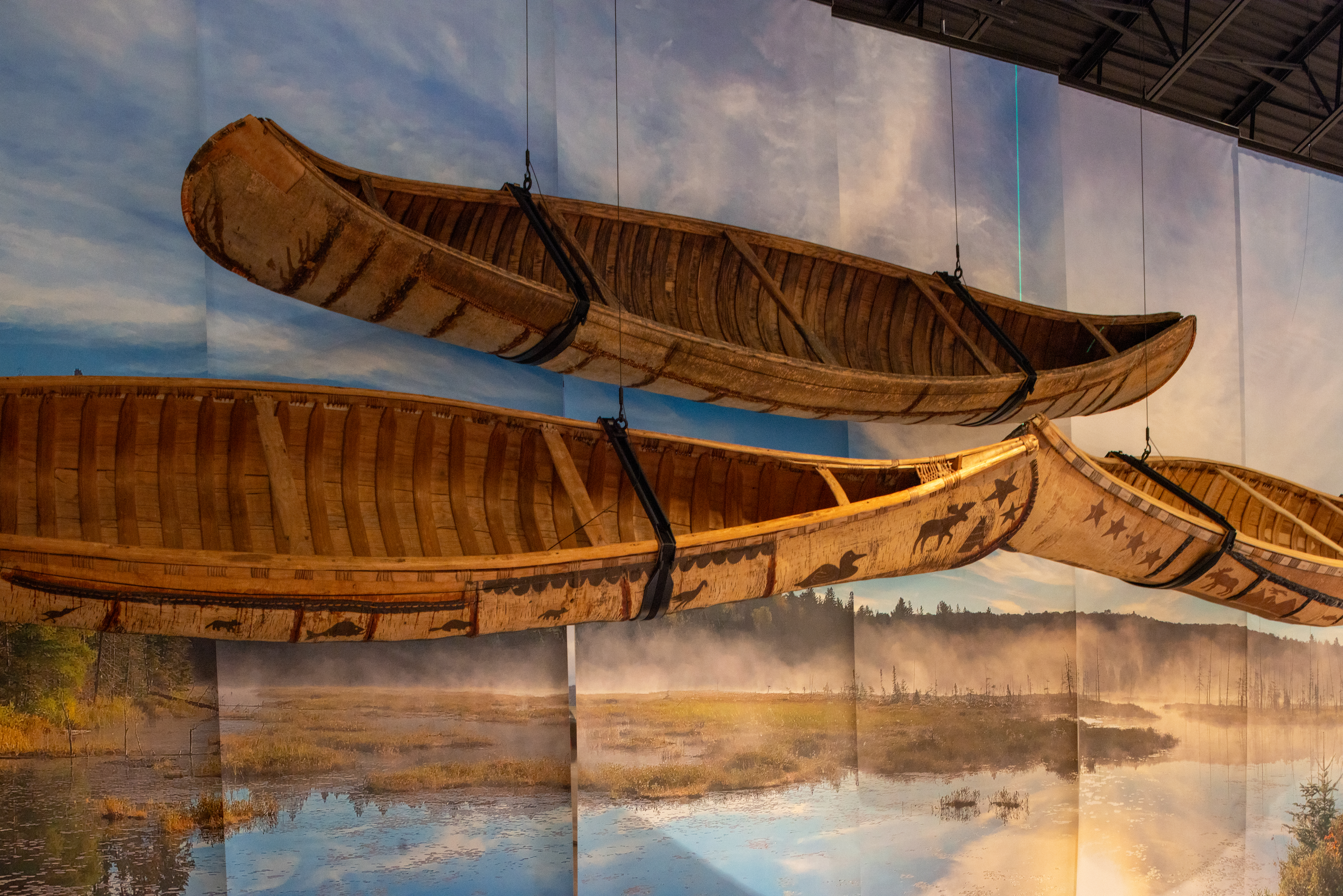 Several canoes mounted to a wall against a nature background