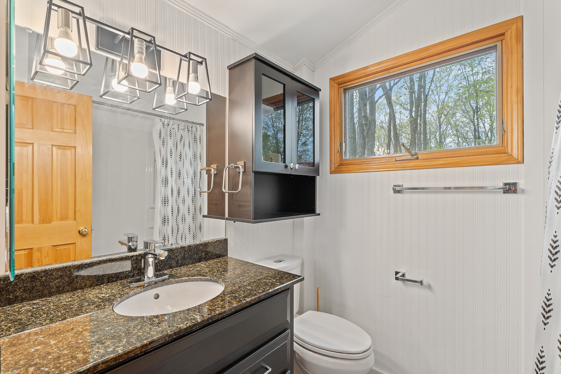A bright bathroom with a toilet, a sink, and a shower tub combo.