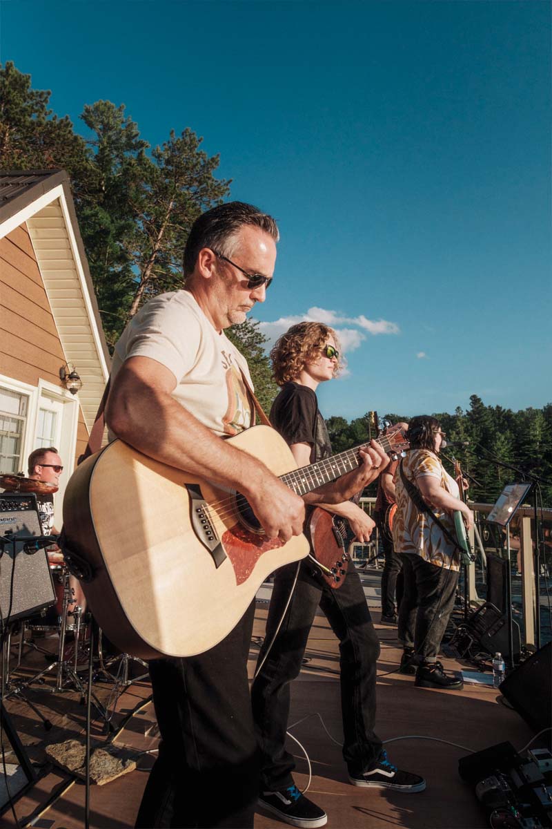 Close up of two people playing guitar with their bandmates in the background