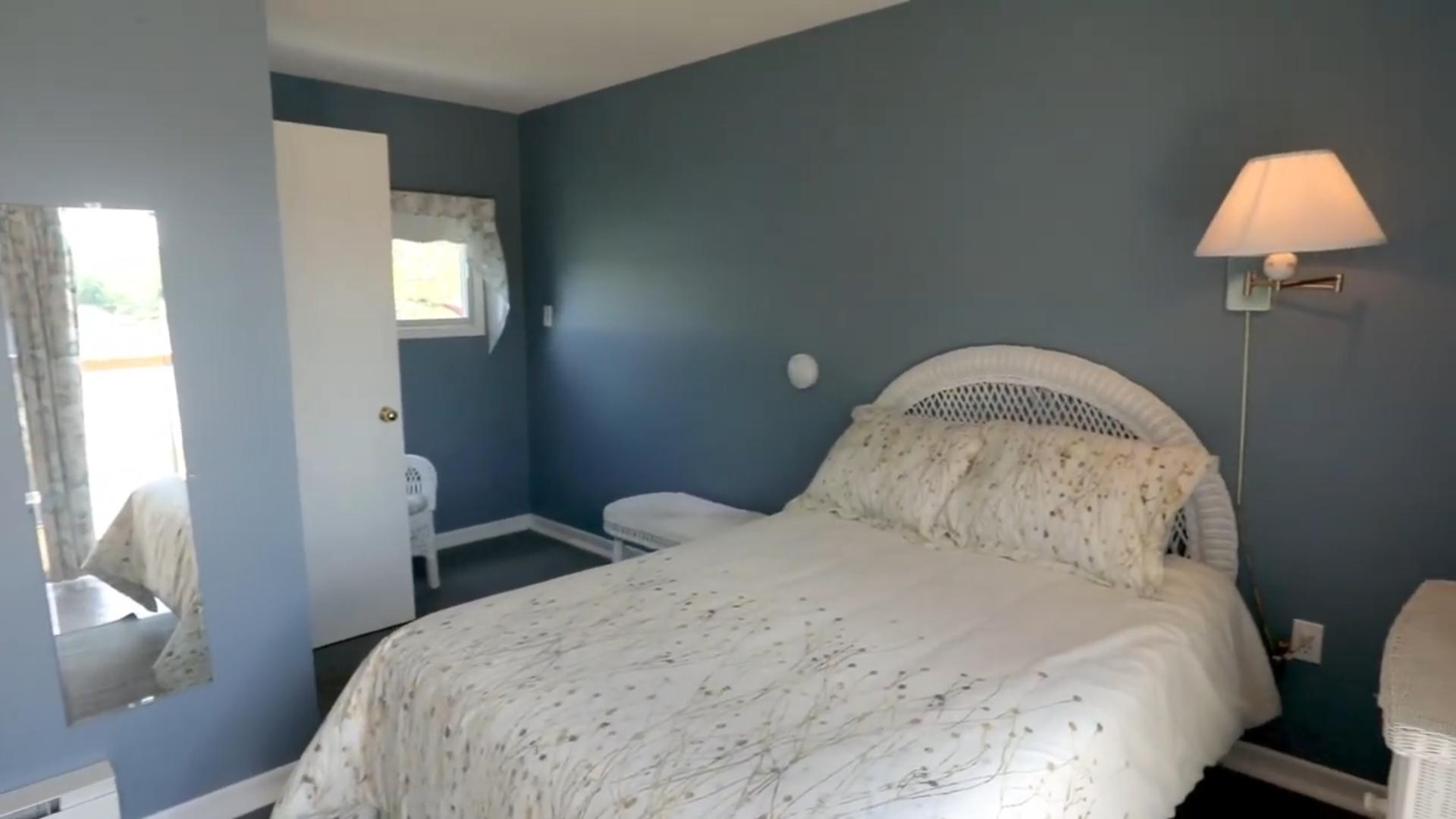 A grey-blue painted bedroom with a white bed