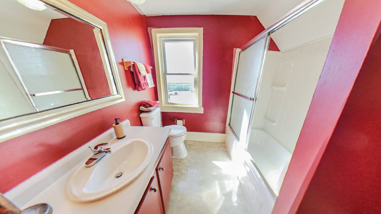 A red bathroom with a glass shower facing the vanity