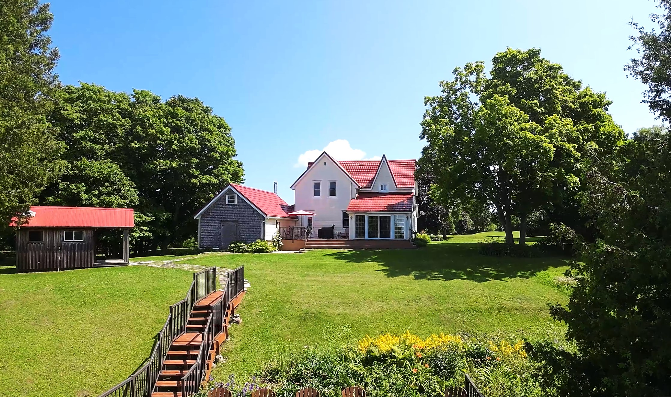 A large white house with a red roof on a large grassy lawn