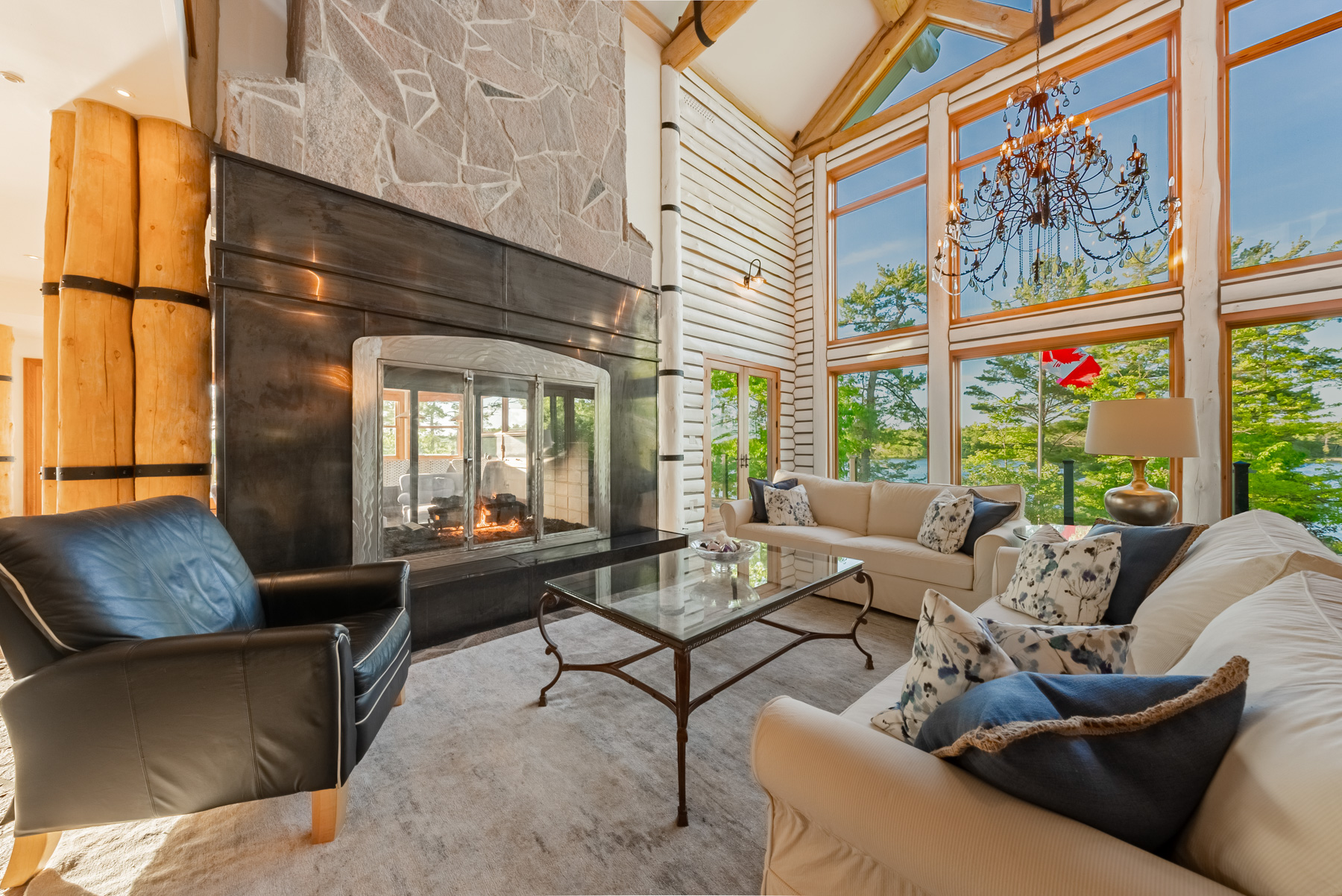 On a carpeted area, a couch faces a stone fireplace next to a large window