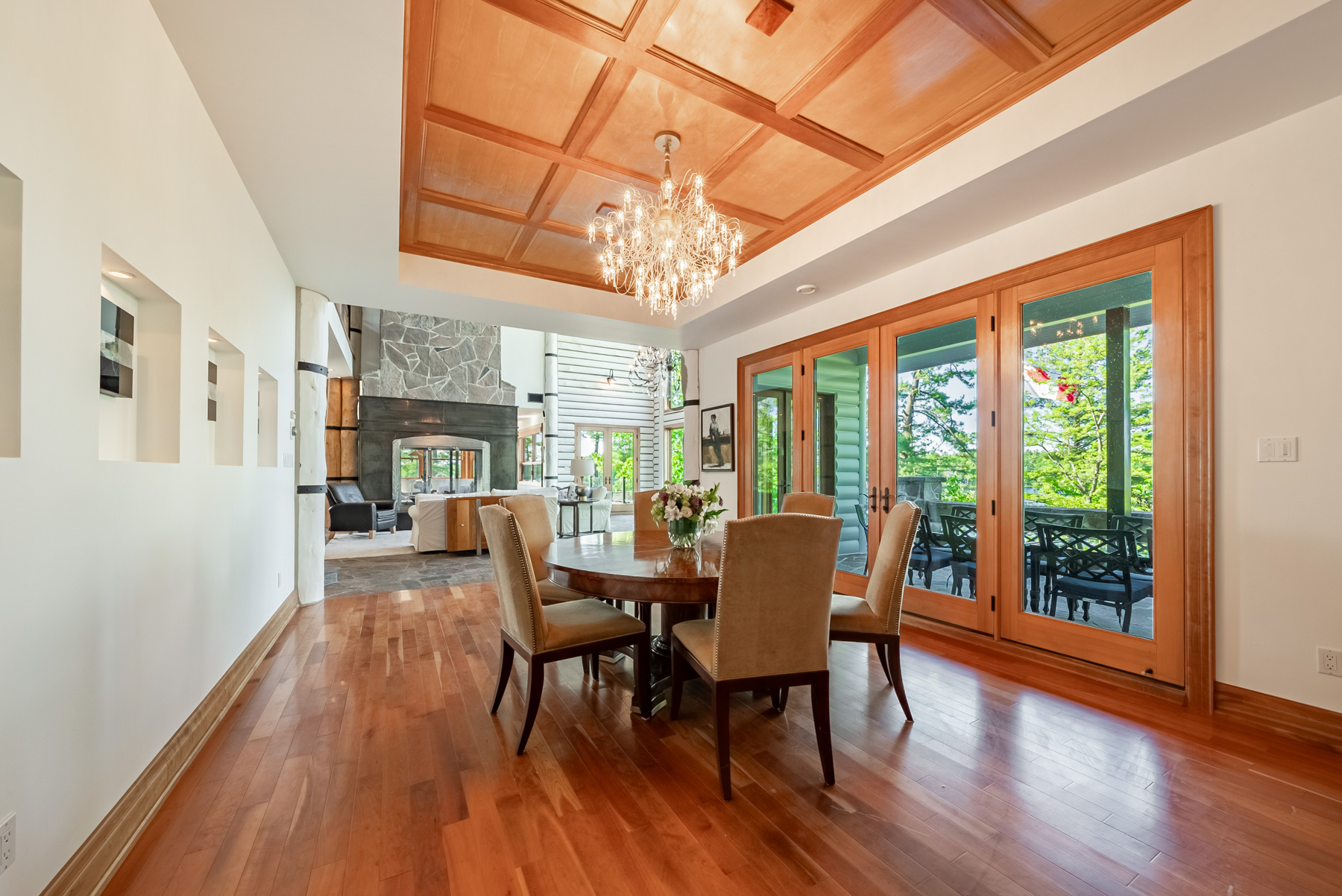 A dining table with brown chairs next to a large window in a large white room
