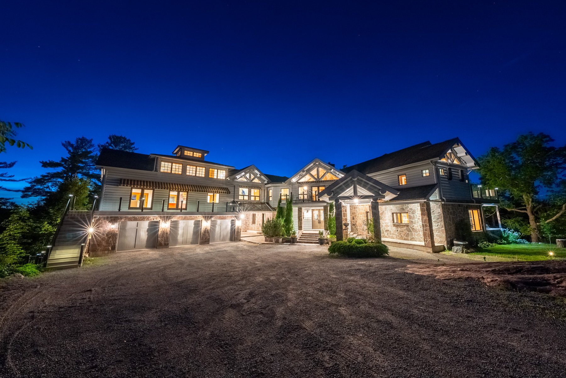 From the driveway, a large house with its lights turned on at night