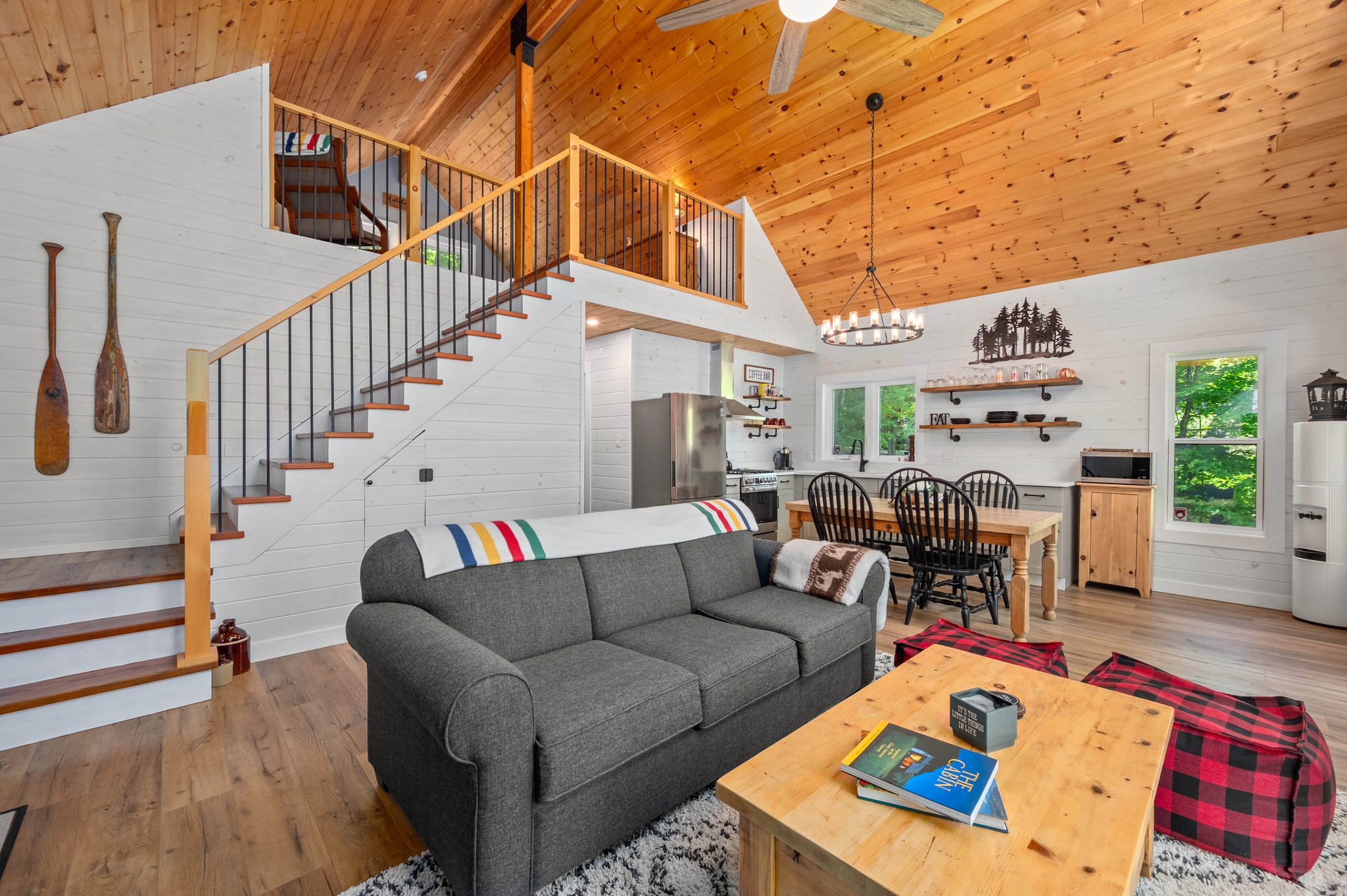 A grey couch with a wood coffee table in front. Behind, a staircase leads upstairs