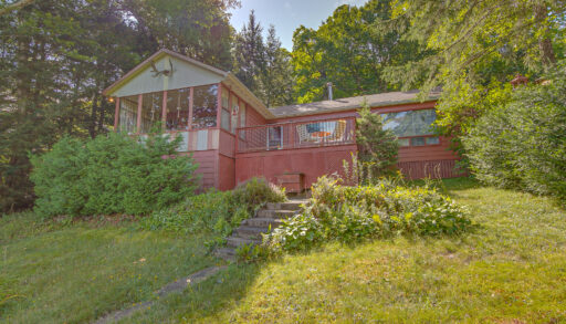 A red bungalow cottage on a grassy hillside