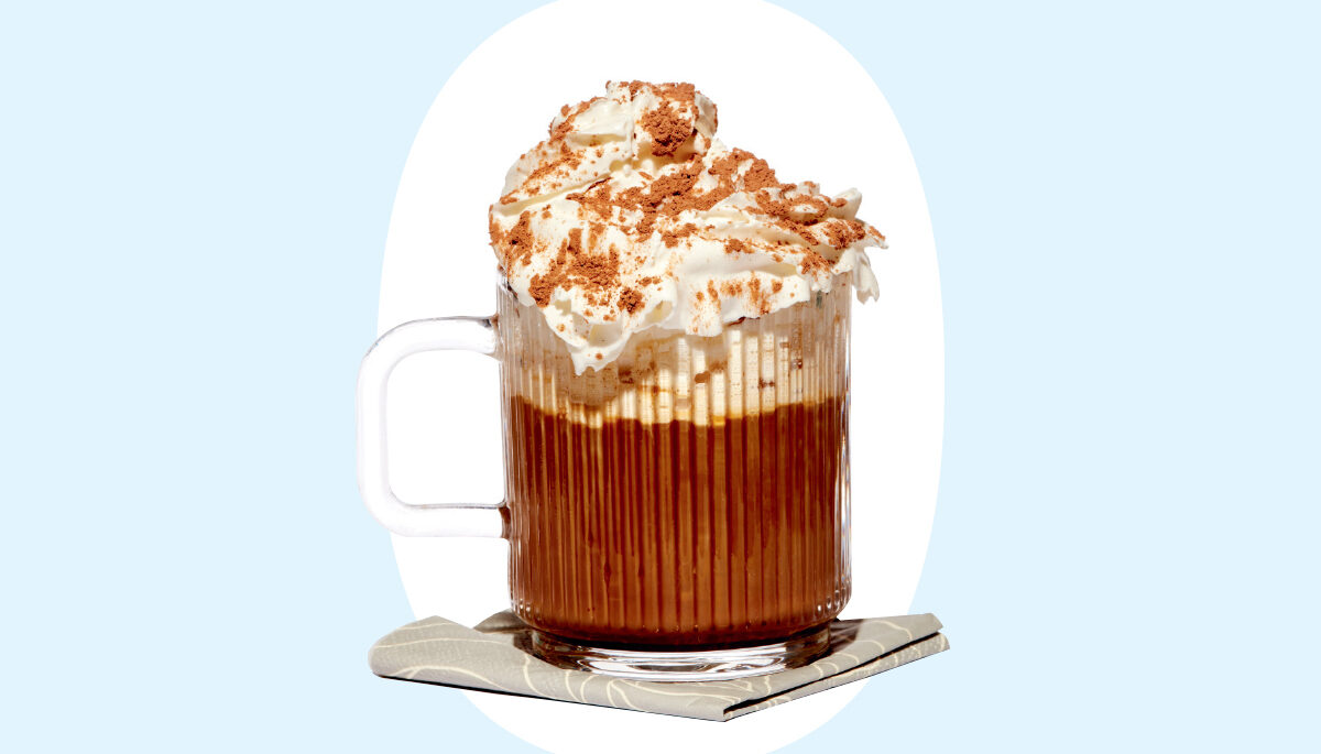 a photo of a dark drink in a clear mug with whipped cream on top