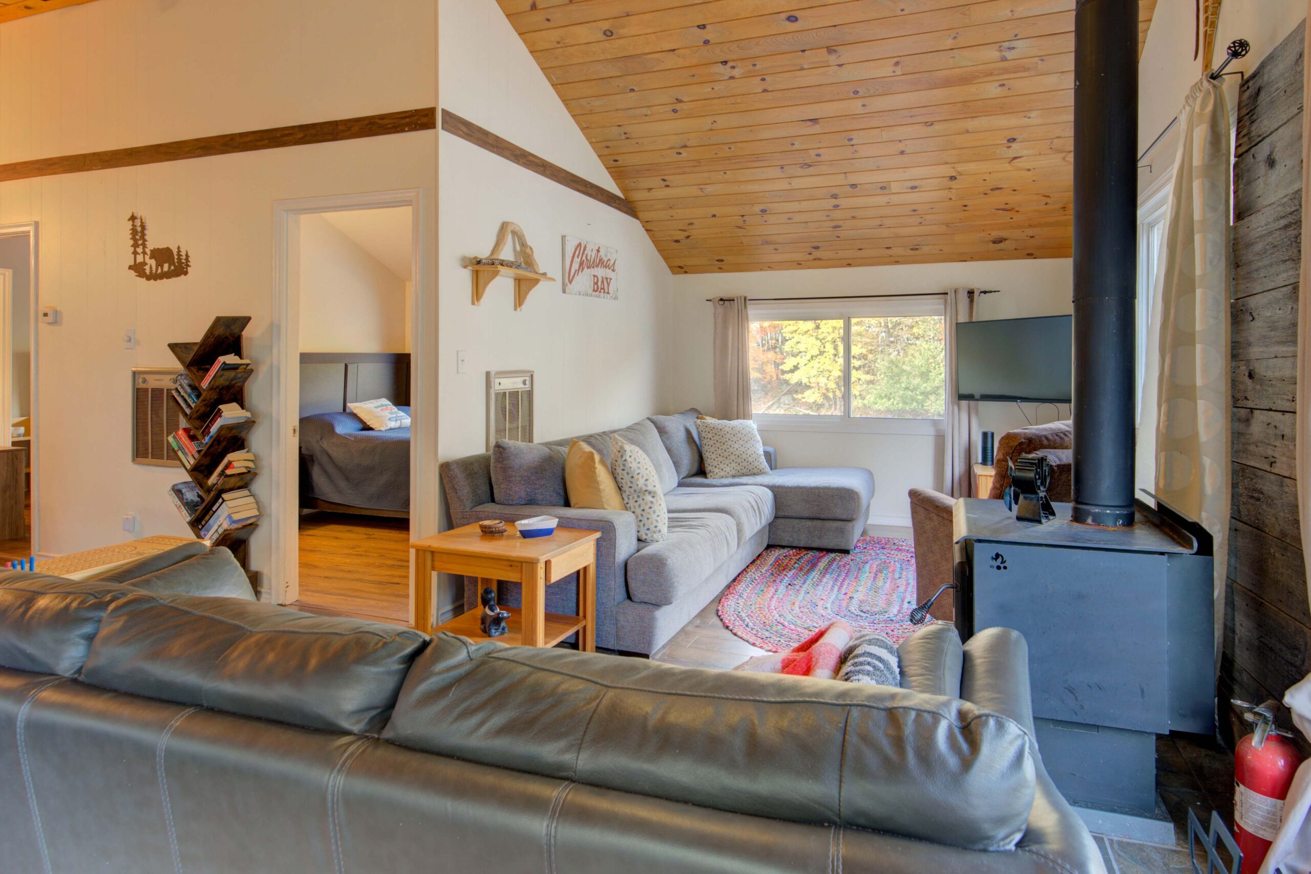 a grey leather couch faces another grey couch in a cozy living room with bright windows