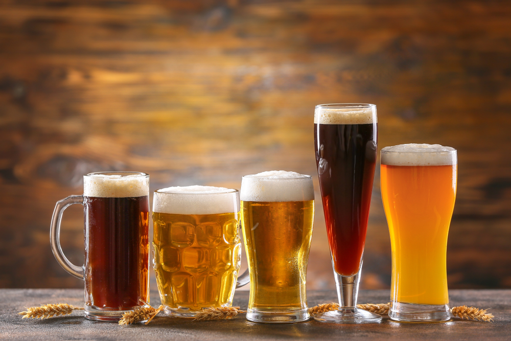 Five different beer glasses, filled with beer, lined up on a table
