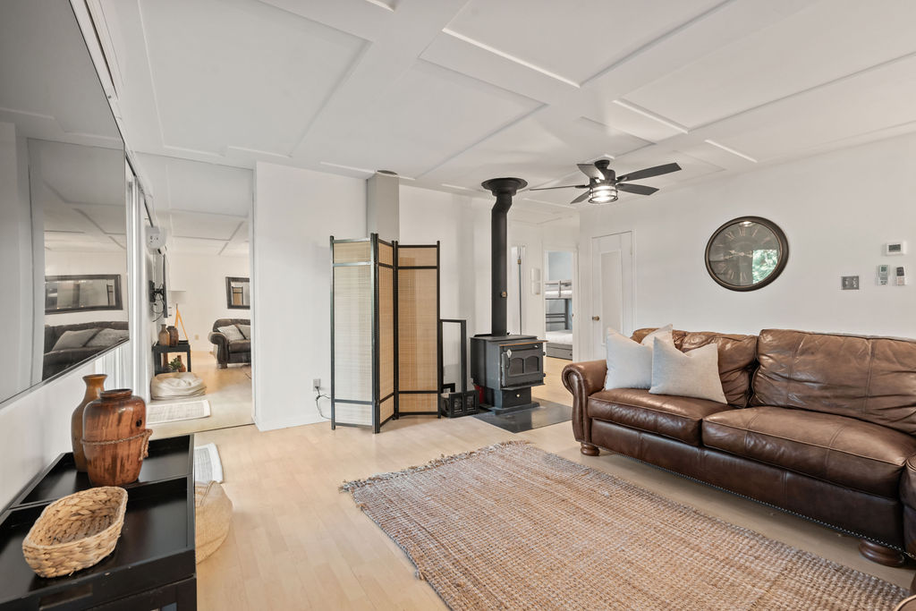 A spacious living room with a wood stove, a brown leather couch, and a large carpet