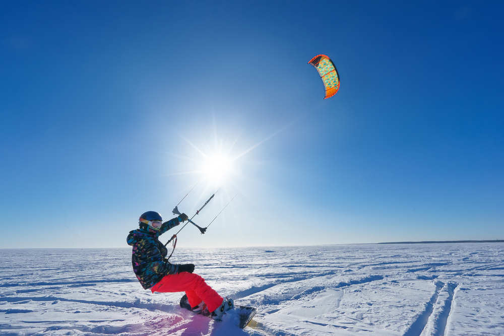 A man snowkiting on a snowboard