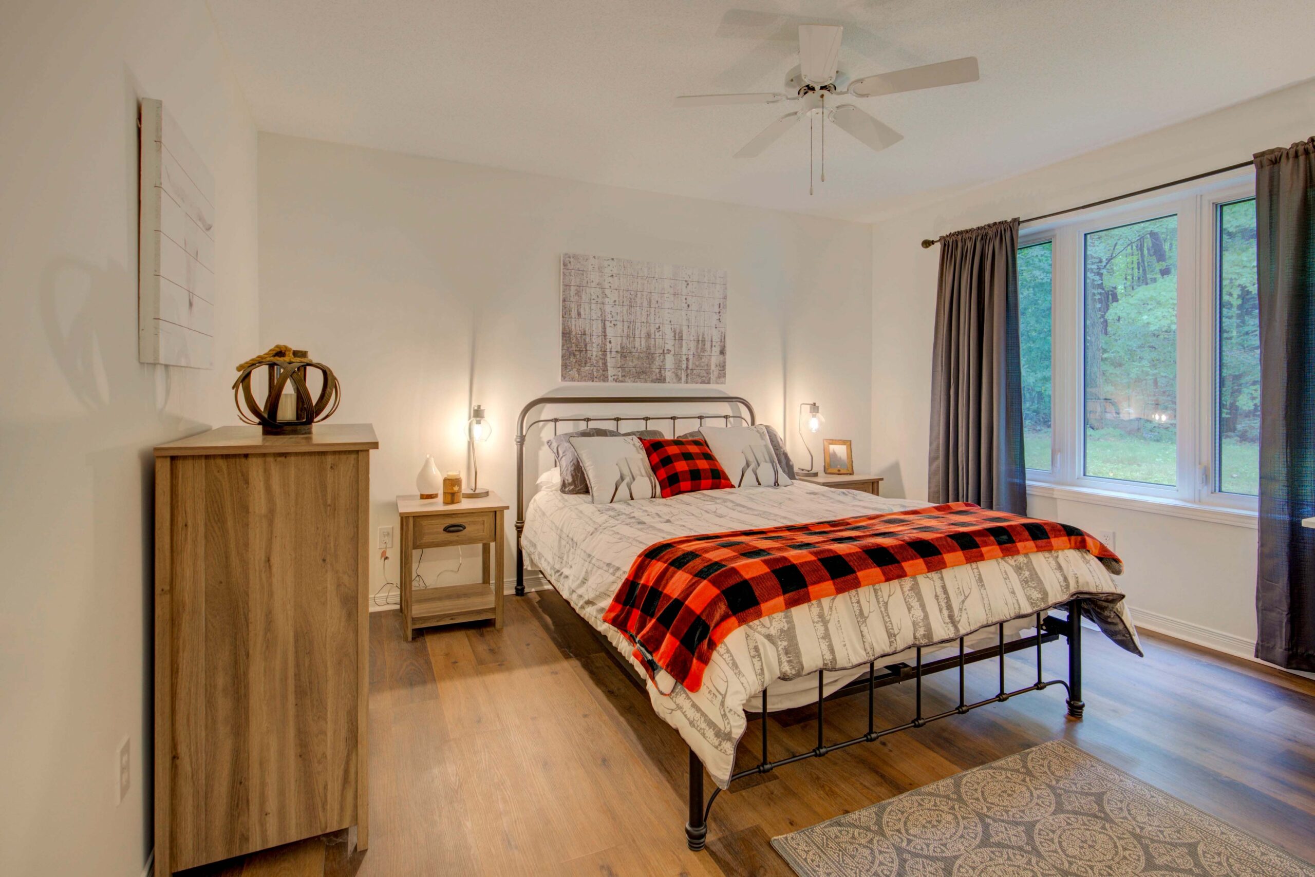 A white bed with a black-and-red checked blanket at the end