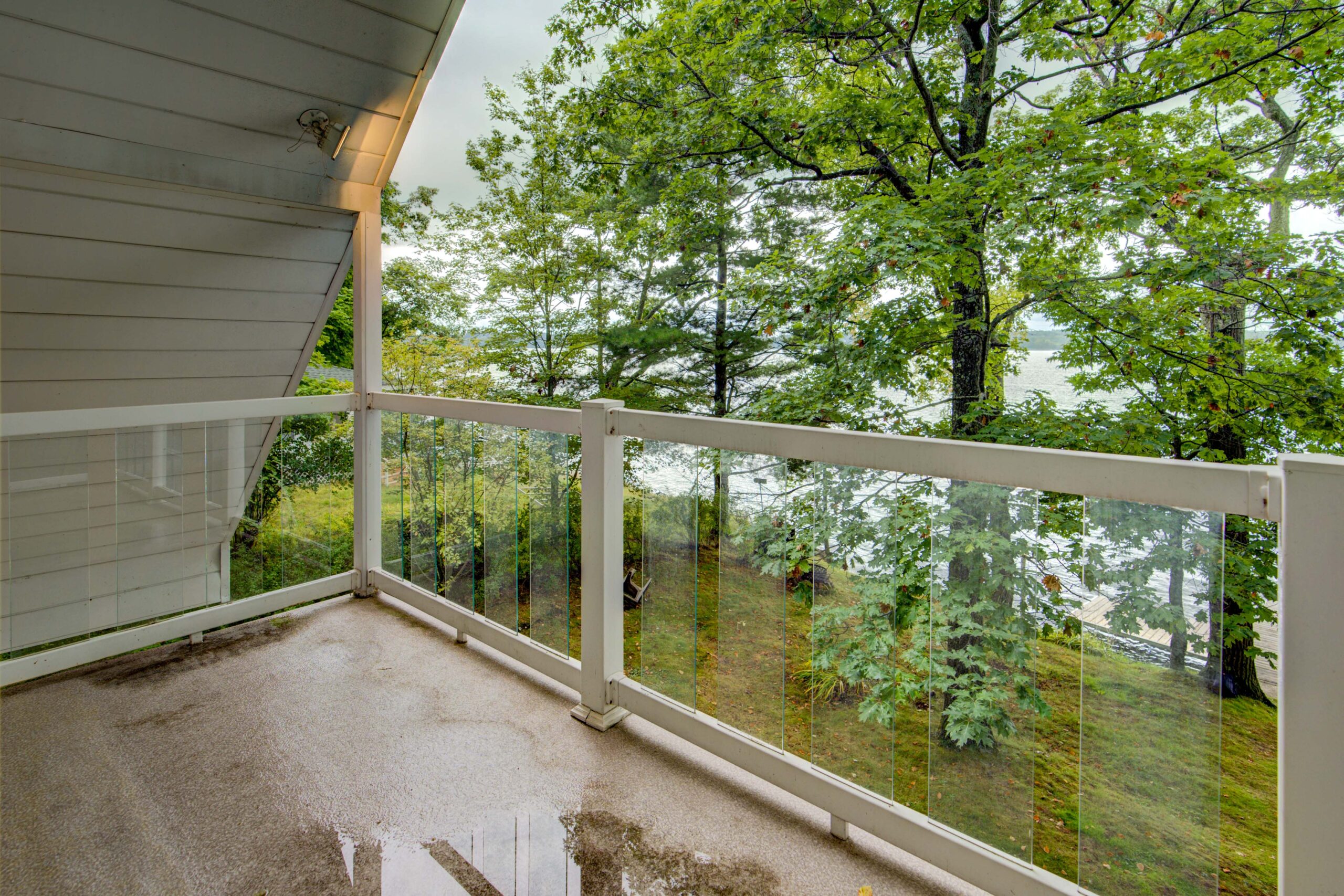 A small concrete balcony with glass railings faces the lake