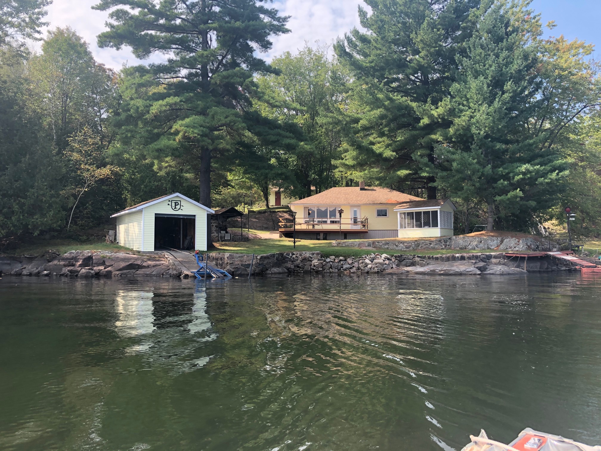 A brown bungalow cottage next to a green lake