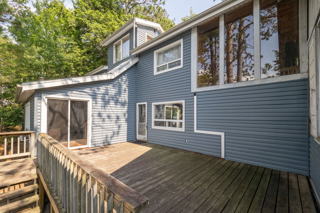 Side view of the cottage showing entrance and wraparound wooden deck