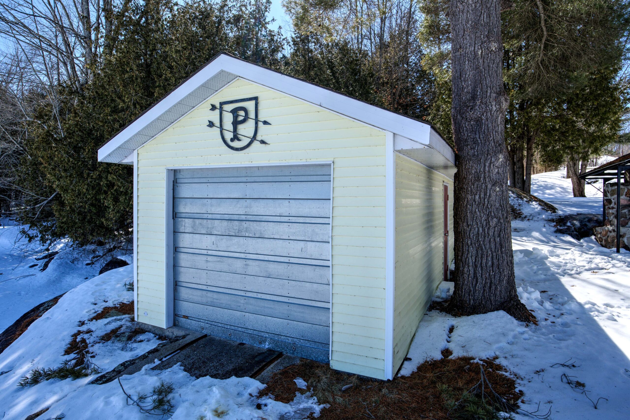 A pale yellow boathouse with a metallic door