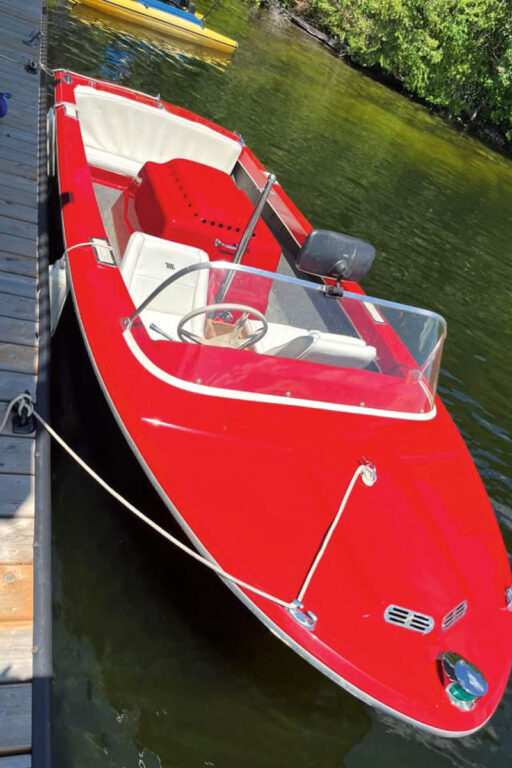 Red Correct Craft ski boat tied to a dock on the water