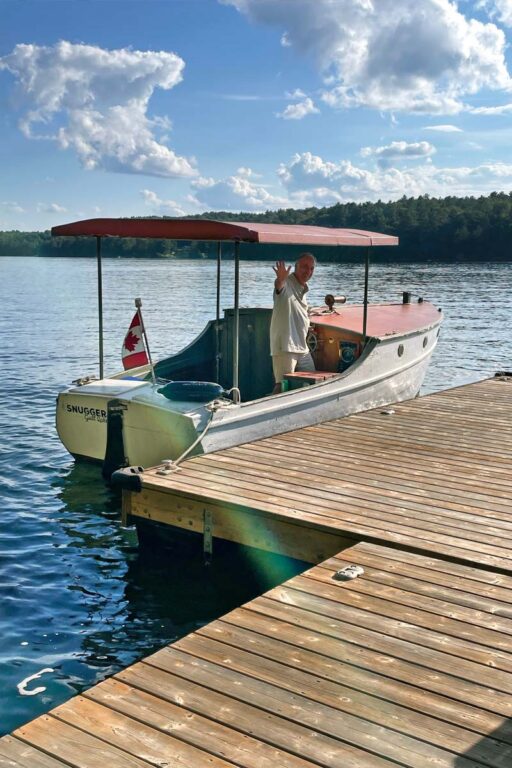 Man standing in a docked white and red wooden show boat.