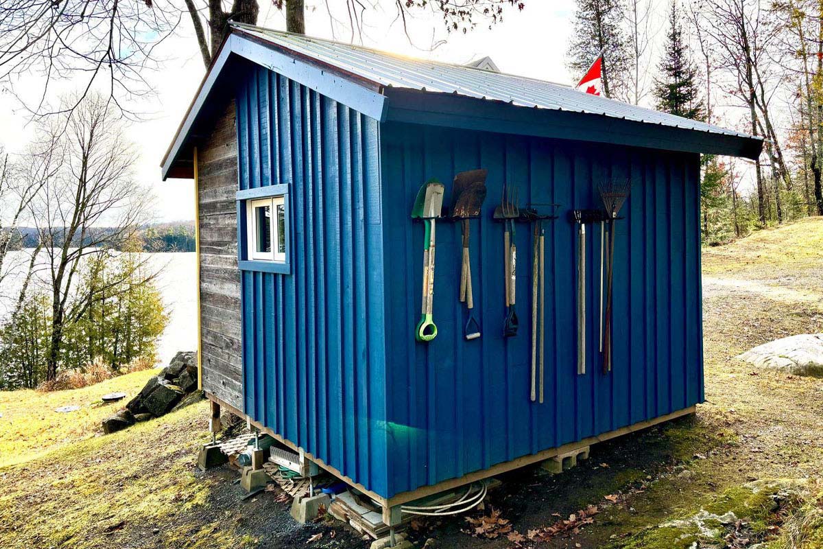 A row of garden tools hung on an outside wall of the shed.
