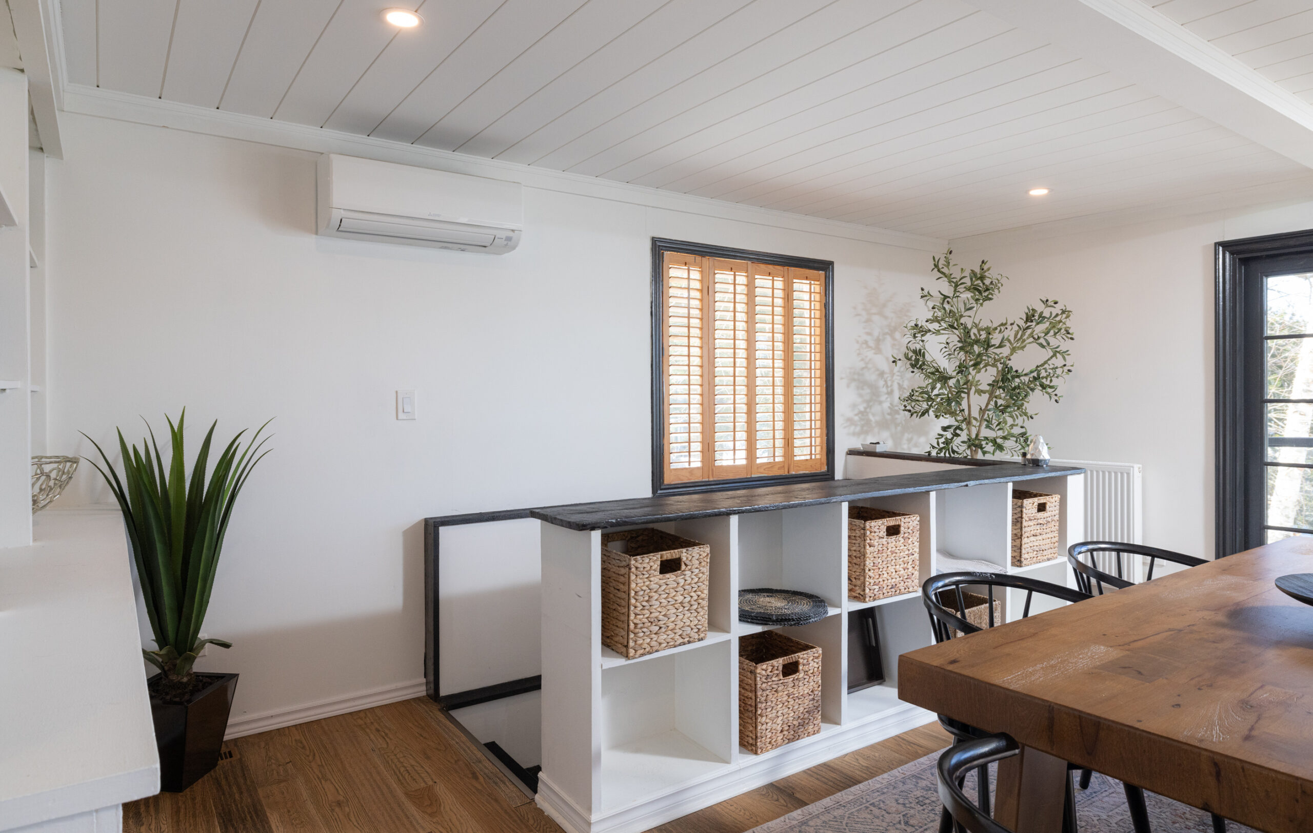 In a white room, a set of cubed storage shelves frame the rail on the way to the basement