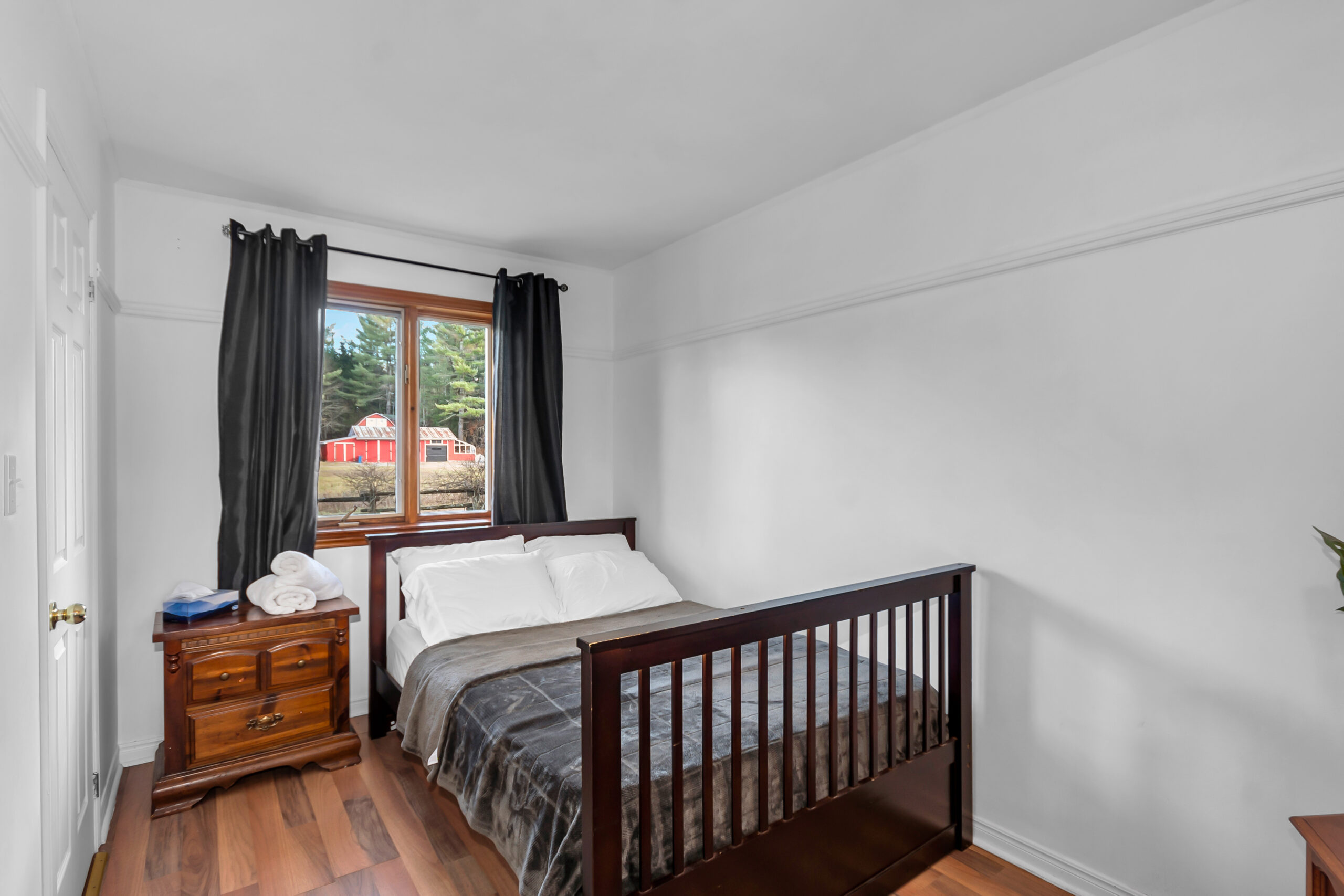 A dark wood bed frame with a grey cover in a white room