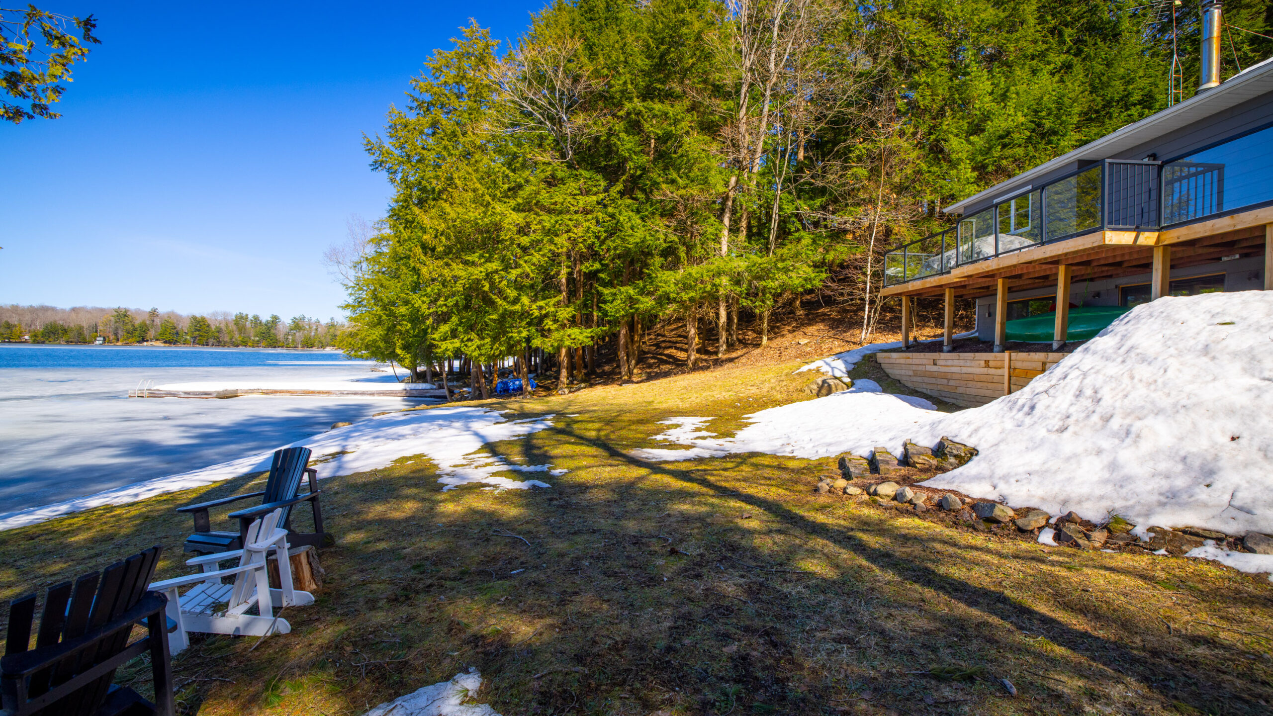 A yellow-green lawn on a slight hill leads down to the frozen lake