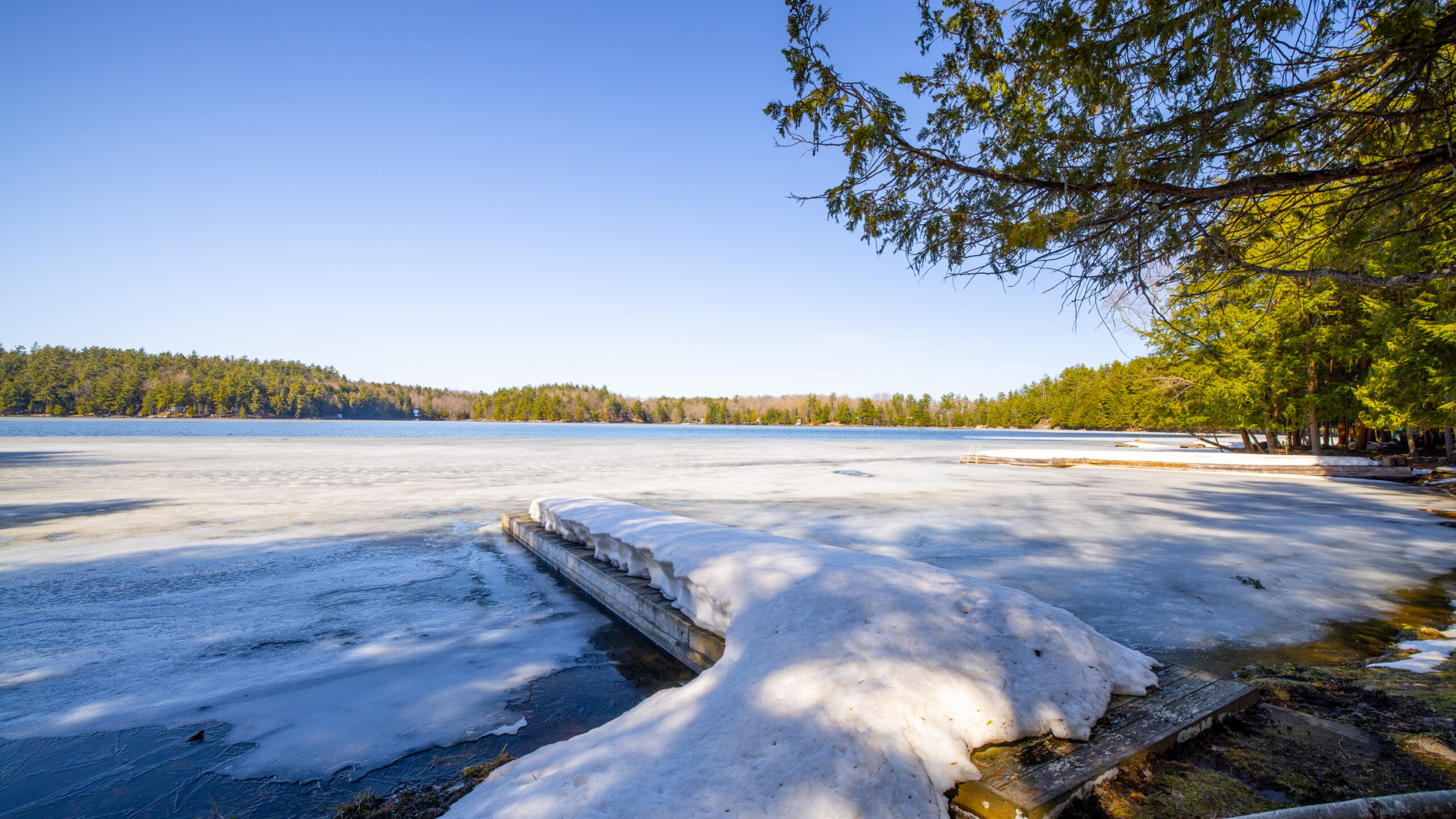 A long dock covered in snow leads out to the frozen lake