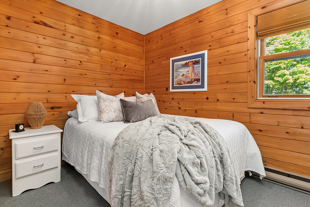 Cozy wood-paneled bedroom in the guest cottage with a large bed and window