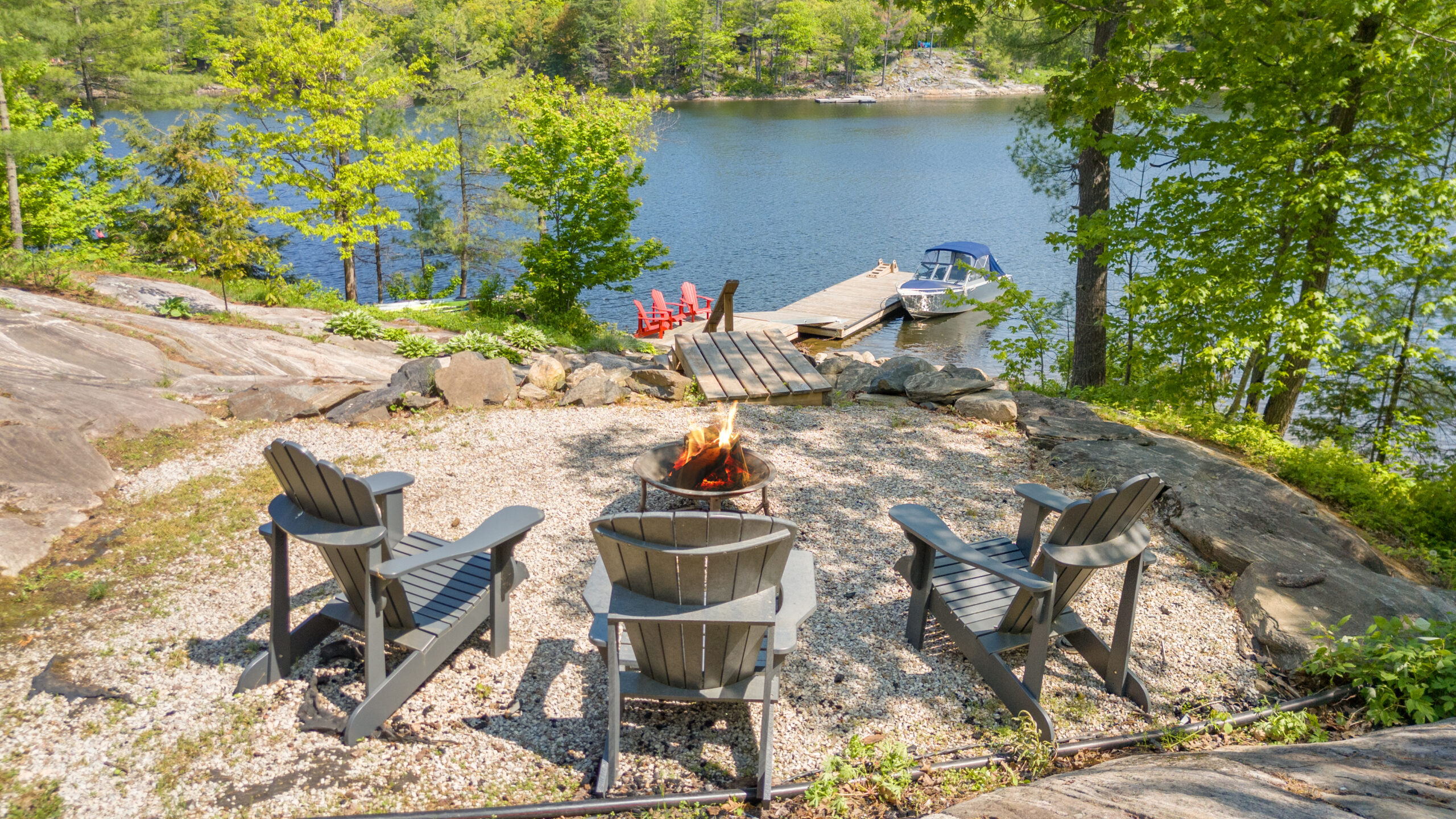 Muskoka chairs around a fire pit overlooking the lake