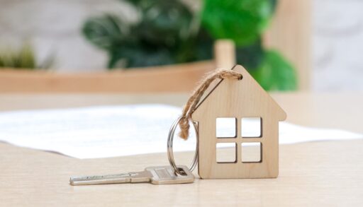 A key fob in the shape of a house next to a piece of paper