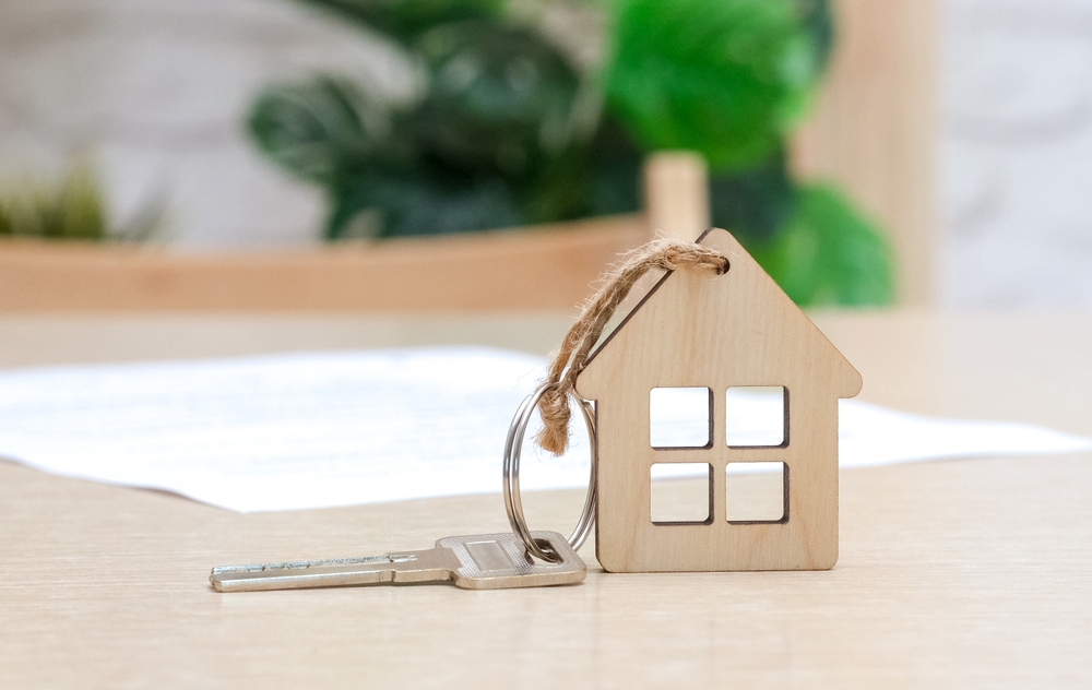 A key fob in the shape of a house next to a piece of paper